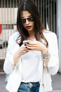 Portrait of young woman using mobile phone in city