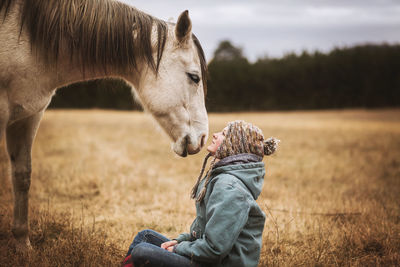 Horse and girl looking at each other in field in the fall