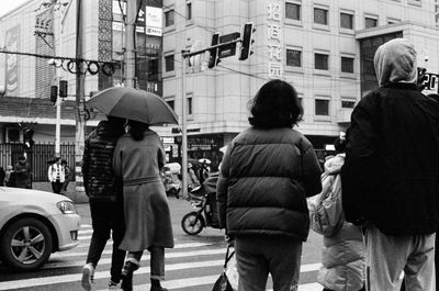 Rear view of people walking on city street