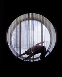 Silhouette of woman doing yoga in the round window