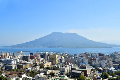 Cityscape by sea against clear sky