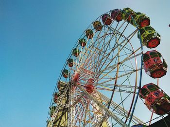 Low angle view of ferris wheel against clear blue sky