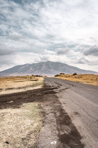 Scenic view of road by mountains against sky