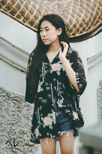 Beautiful young woman standing against wall