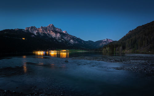 Scenic view of lake against clear blue sky at dusk