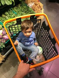 High angle portrait of cute boy sitting in shopping cart