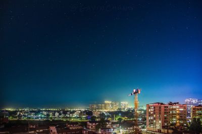 Illuminated cityscape against blue sky at night
