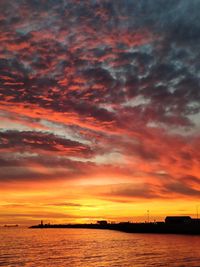 Scenic view of sea against dramatic sky during sunset