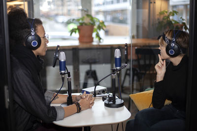 People wearing headphones and sitting at table with microphone