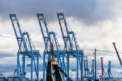 Large blue cranes at the port of tacoma with clouds behind.