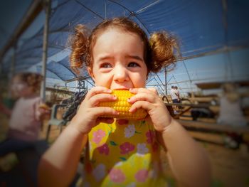 Close-up of cute girl eating corn while standing outdoors