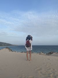 Traveler woman standing at beach against sky