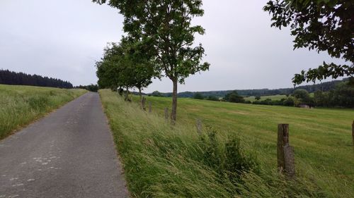 Road amidst field against sky