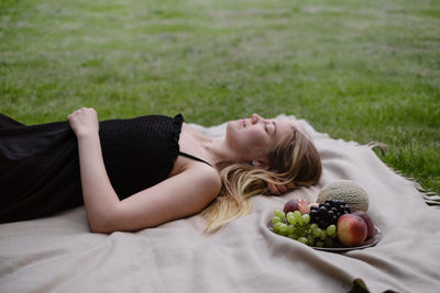 Woman on picnic in green garden on blanket. cheerfully female spend time outdoors, eating summer