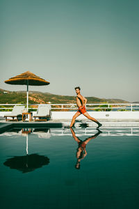 Rear view of man jumping on beach against clear sky