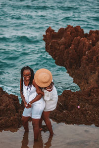 Portrait of two young women standing at beach during sunset 