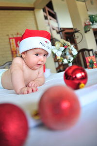 Cute baby girl lying on bed at home during christmas