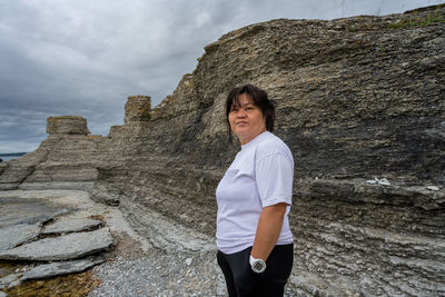 Asian middleged woman standing in front of a limestone formation