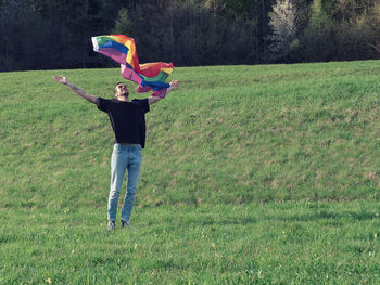 Man throwing rainbow flag at park