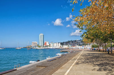 Footpath by buildings in city against sky