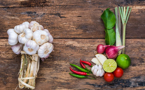 High angle view of garlic and chili peppers on wooden table