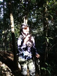 Rear view of woman standing by tree in forest