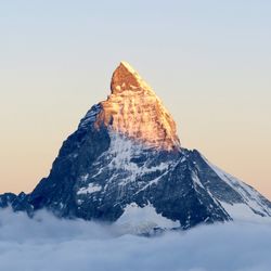 Scenic view of snowcapped mountain against clear sky during sunset