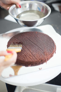 Cropped image of hand applying syrup on sponge cake
