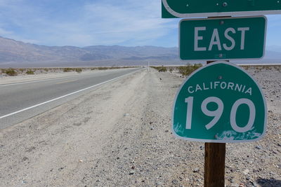 Close-up of road sign california against sky