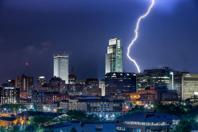 Illuminated buildings in city against sky at night