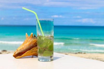 Close-up of drink on table at beach against sky