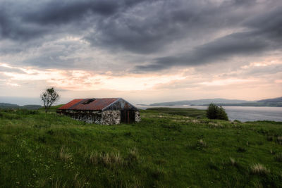 House on field against sky during sunset