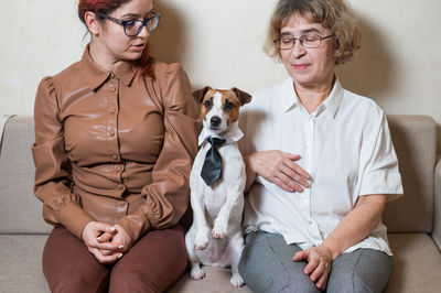 Women sitting with dog on sofa at home