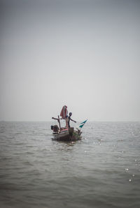 Men in sea against clear sky