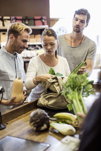 Friends discussing while shopping vegetables at supermarket checkout