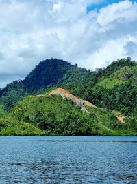 Scenic view of river by tree mountains against sky