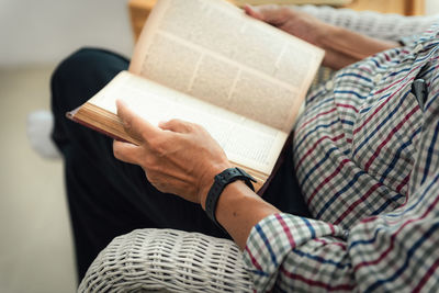 Midsection of man reading book while resting at home