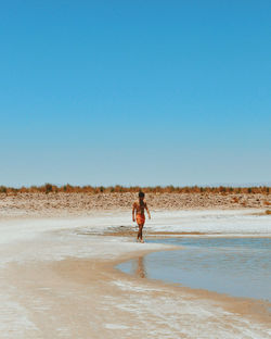 Man standing on beach against clear sky