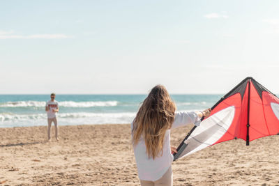 Young woman holding a kite and playing on the mediterranean coast on the beach in a sunny day