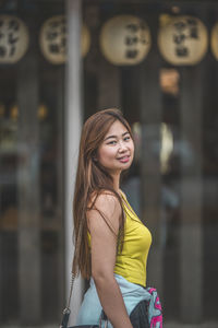 Portrait of smiling young woman standing against blurred background