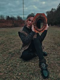 Portrait of young woman holding hat on field