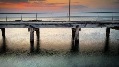Bridge over sea against sky during sunset