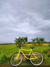 Bicycle parked on field against sky