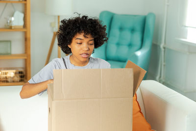 Portrait of smiling young woman sitting on sofa at home