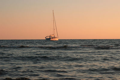 Sailboat in sea against sky during sunset