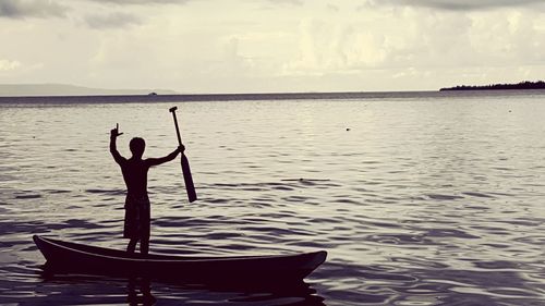 Silhouette man gesturing while sailing boat in lake