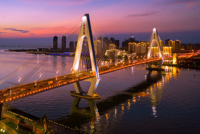 Illuminated bridge over river at night