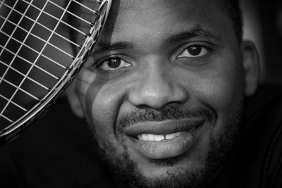 Close-up portrait of man holding tennis racket