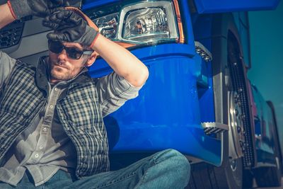 Low angle view of man sitting by truck