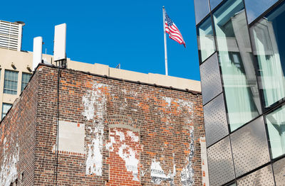 Low angle view of flag against buildings in new york city with clear blue sky 